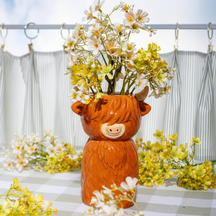 Highland cow shaped vase filled with flowers on gingham tablecloth