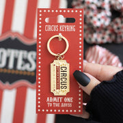 Keyring on red packaging card with striped cup on wooden surface