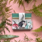 Secret Garden hedgehog purse on pink background with foliage