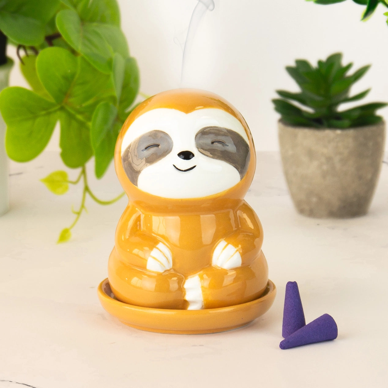 Orange sloth incense burner on tray with smoke and incense cones
