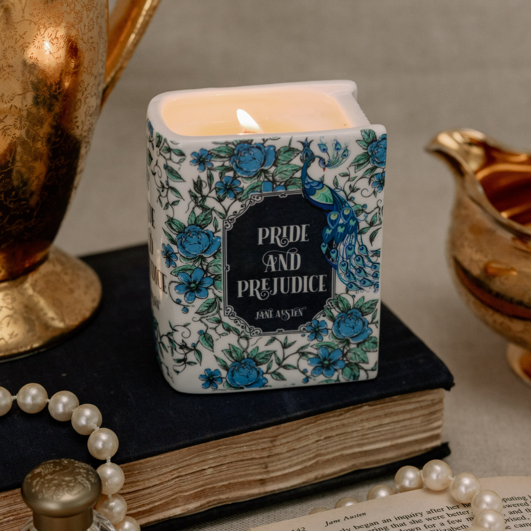 Pride and Prejudice book candle lit on vintage book with pearls and gold accents