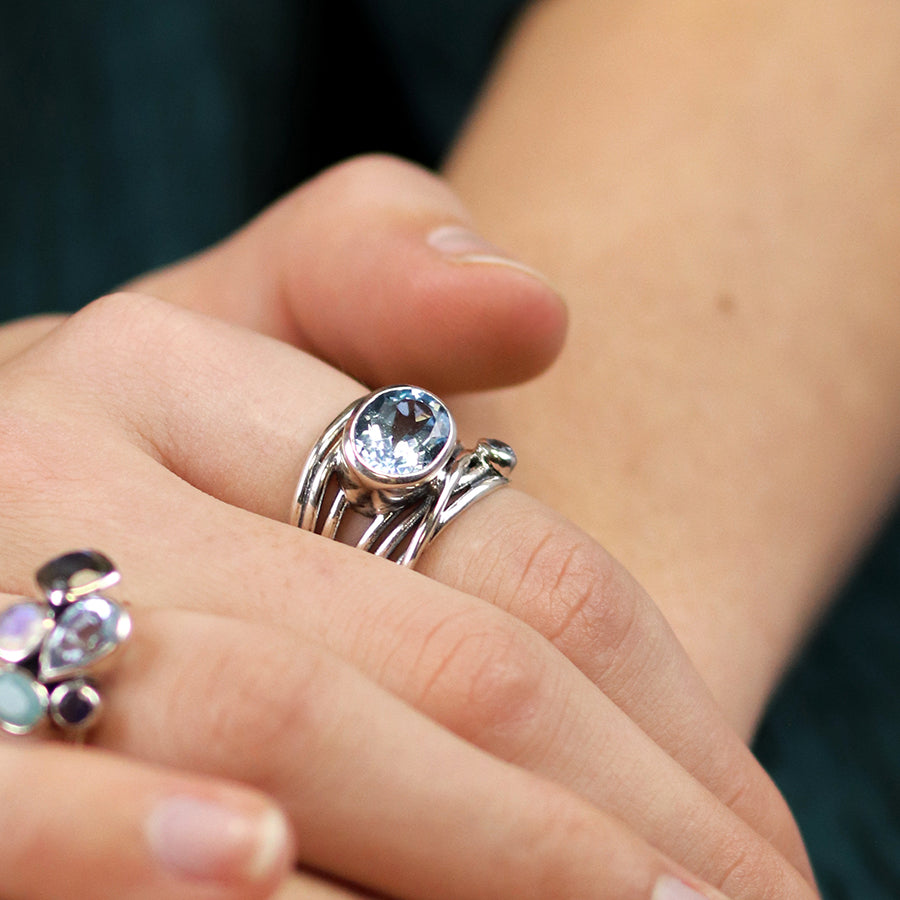 Sterling silver blue topaz multi strand ring worn on hand showing large faceted gemstone.