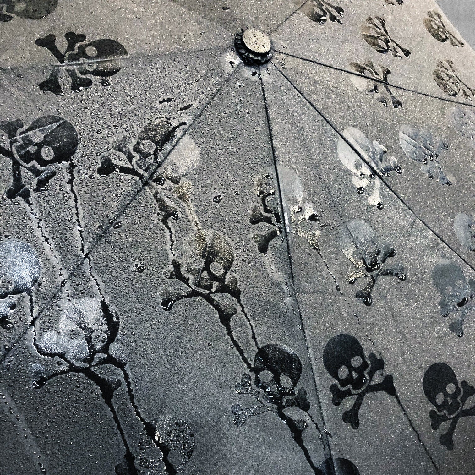Close-up of hidden skulls umbrella wet fabric with glossy skull details
