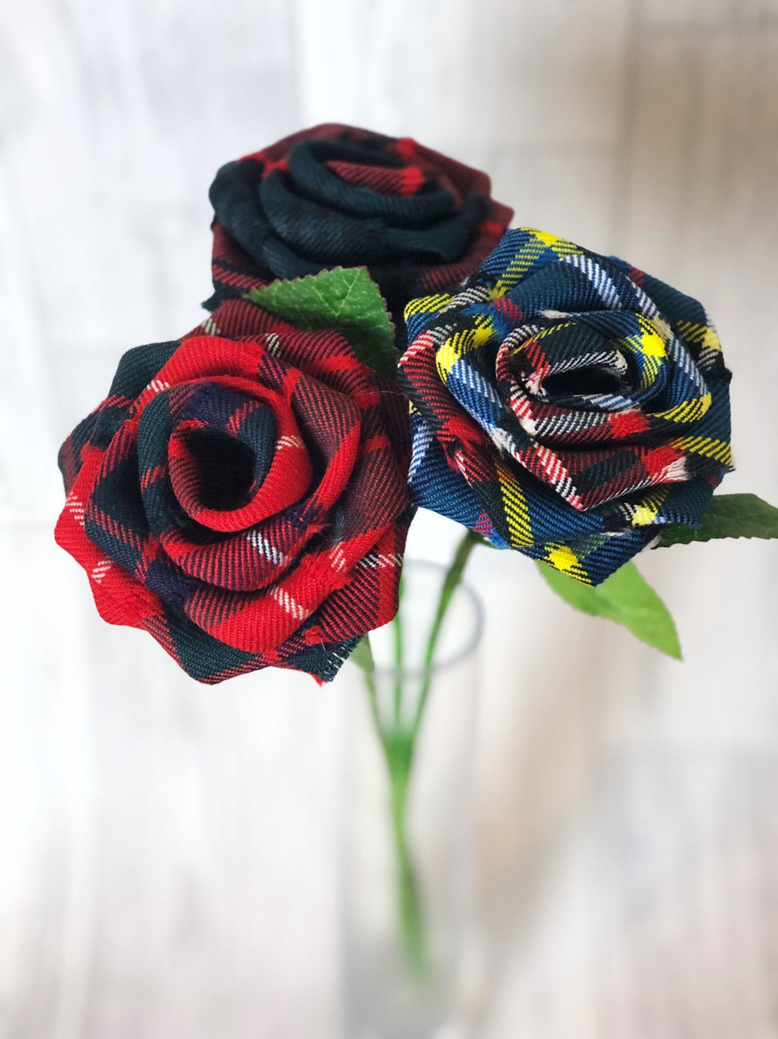 Tartan stem roses trio with green leaves in a glass vase