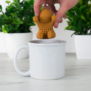 Hand placing silicone Sloth Tea Infuser into white ceramic mug.