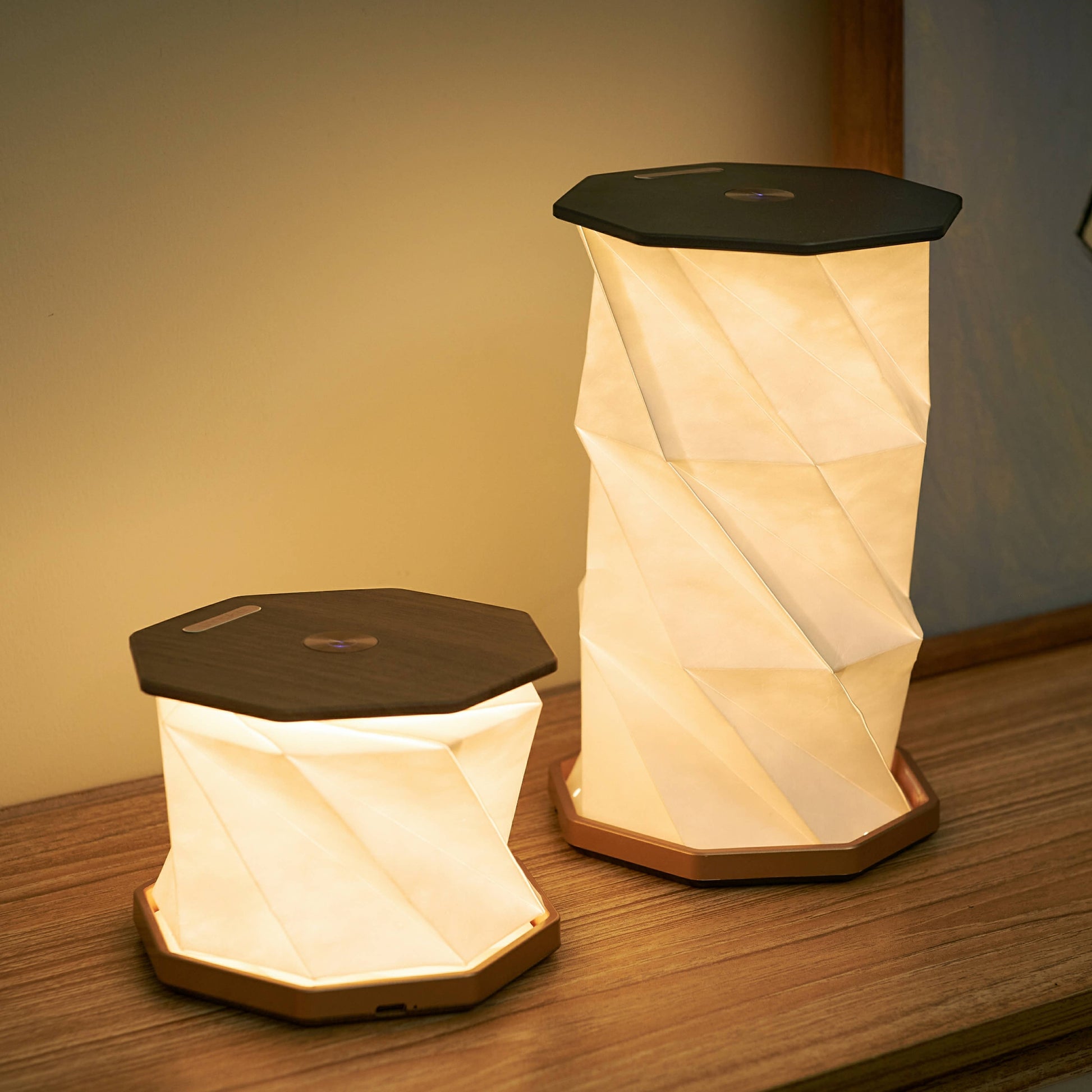 Twist Hexagon lamp in walnut finish shown in two sizes on wooden surface