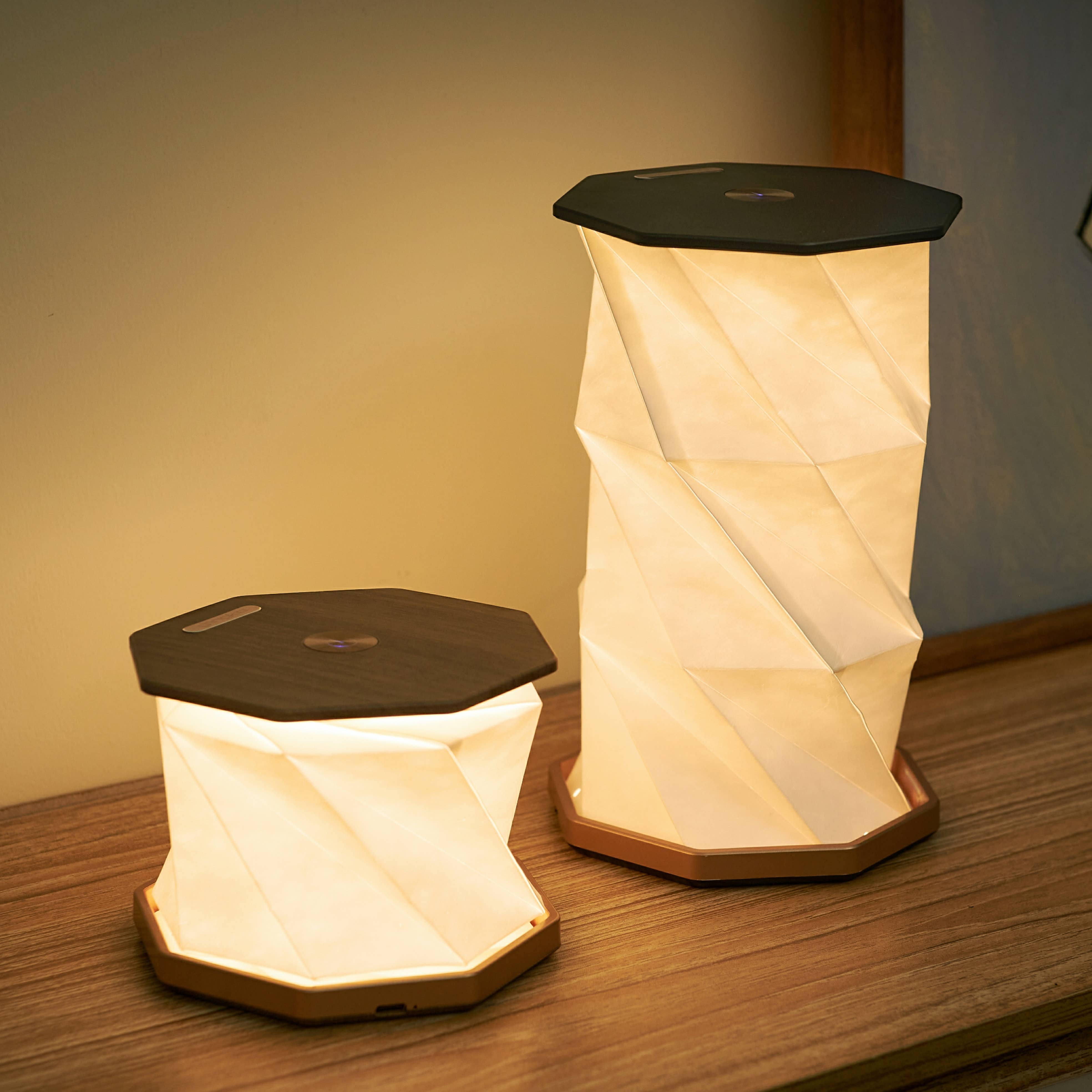 Twist Hexagon lamp in walnut finish shown in two sizes on wooden surface