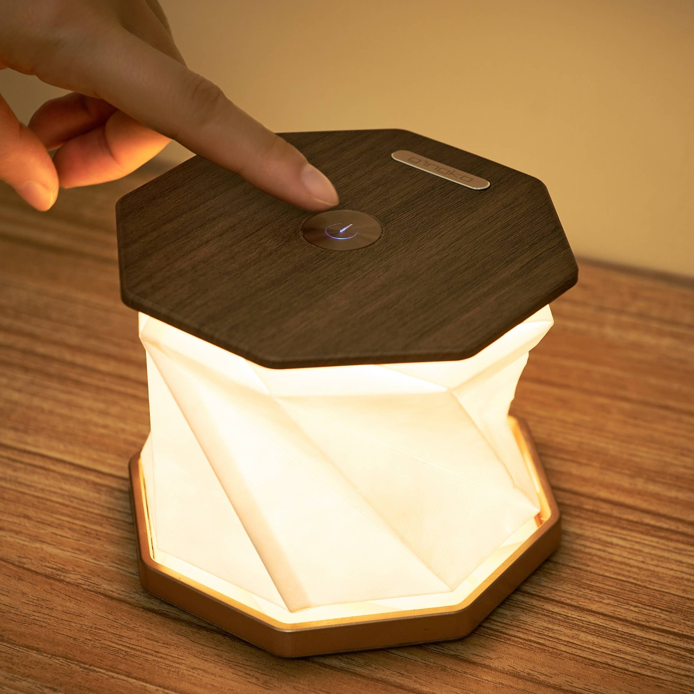 Close-up of Twist Hexagon lamp walnut top with touch button, glowing