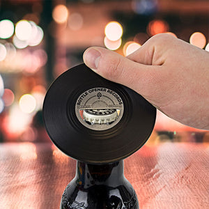 Hand using vinyl record bottle opener to open a beer bottle