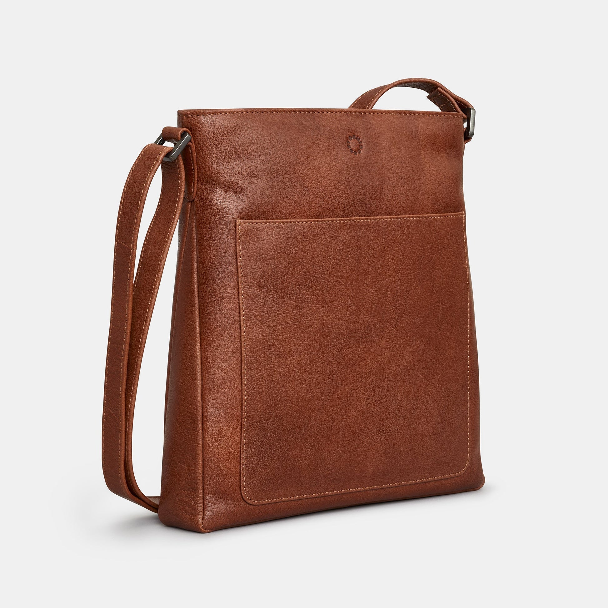 Brown leather crossbody bag side view showing front slip pocket on grey background