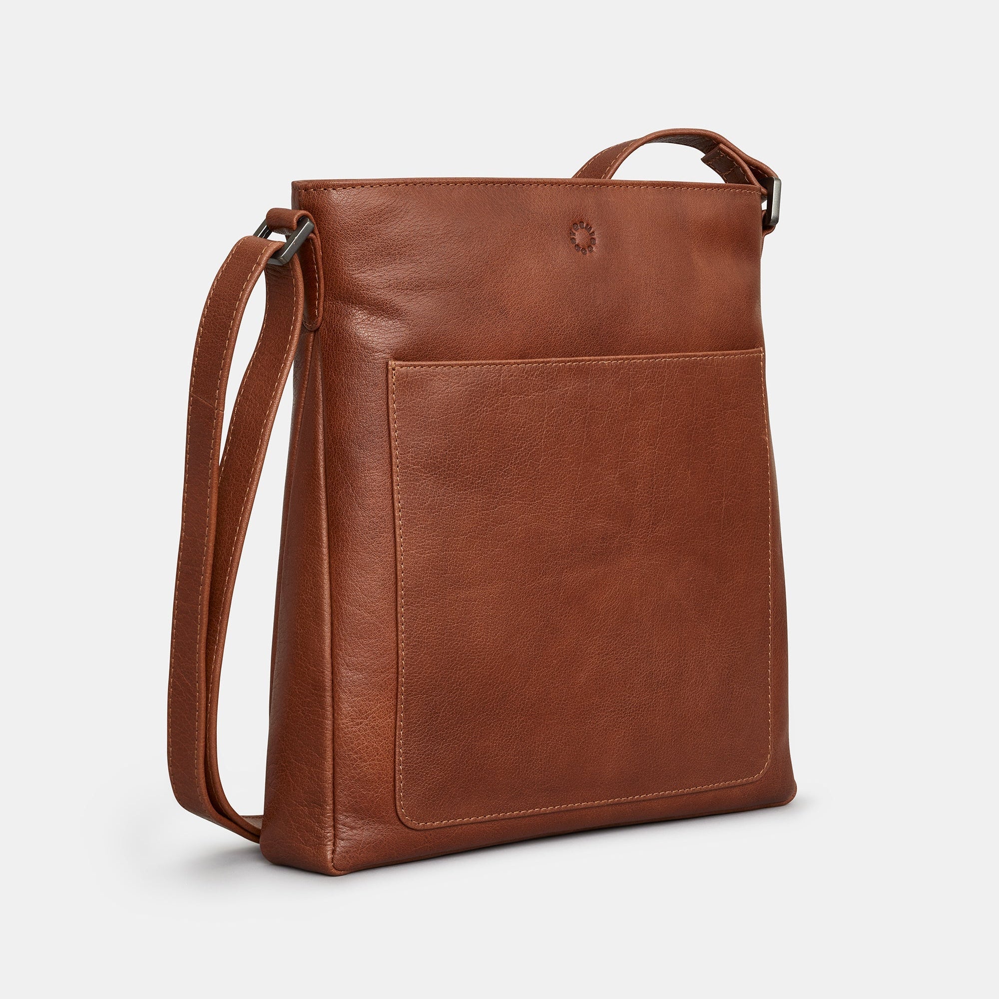 Brown leather crossbody bag side view showing front slip pocket on grey background