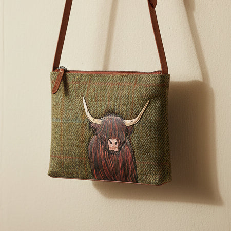 Highland cow crossbody bag in green Harris Tweed hanging on beige wall