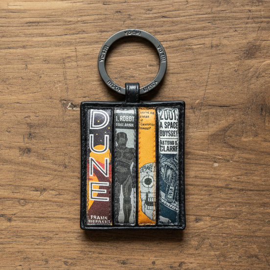 Sci-fi book club keyring showing four book spines on wooden surface