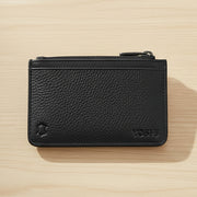 Black leather zip-top card holder back view with Yoshi branding on wood surface