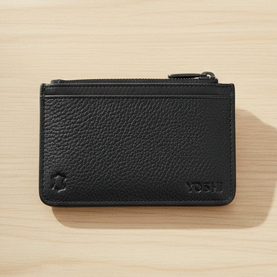 Black leather zip-top card holder back view with Yoshi branding on wood surface