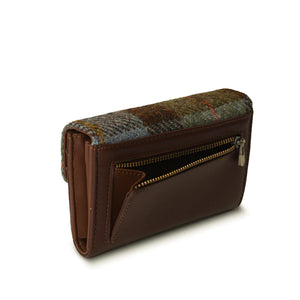 The back of the chestnut and blue Harris tweed purse features a convenient zippered pocket made from brown PU leather. The pocket is a useful size for storing items such as a coins or keys, and is secured with a durable zipper. The brown PU leather adds a touch of sophistication to the overall design of the purse.