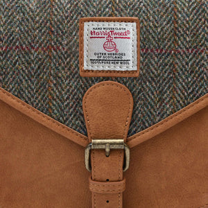 Close up of the front of the saddle bag showing the Harris Tweed logo with the Chestnut brown herringbone pattern behind.
