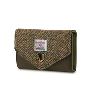 A side view of a chestnut herringbone Harris Tweed purse, showing the popper button closure and authentication label. The purse is made from durable wool and has a stylish, timeless design.