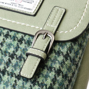 Close up of the buckle on the front of the backpack with the Green Dogtooth Harris Tweed fabric behind. 