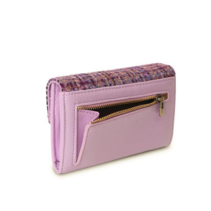 An image of the back of a violet dogtooth Harris tweed purse, featuring a rear zipped pocket. The pocket is the perfect size for storing small items such as keys, the zipper closure keeps them secure. The classic dogtooth pattern in rich violet can be seen on the front of the purse, and the sturdy handles are visible on either side. This stylish and practical accessory is perfect for adding a touch of sophistication to any outfit.