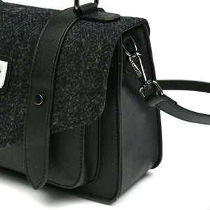 The Isnalder Black Herringbone Harris Tweed satchel style handbag from the right handside showing the adjustable, removable shoulder strap and the Harris Tweed fabric. 
