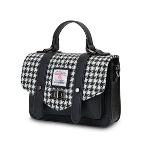 Side angle of th Islander black and white dogtooth satchel style handbag without the shoulder strap but showing the side hooks where the strap would attach.