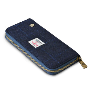 At a side angle the Harris Tweed purse has a bronze coloured zip and is finished with a navy and blue tartan pattern.