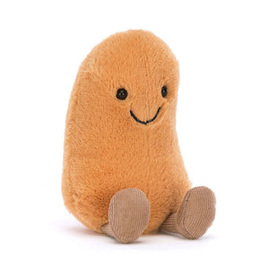 A close-up photo of a Ginger-colored Jellycat Amuseable Bean. This plush toy has a smiling face, tiny arms, and legs. The bean-shaped toy sits upright and appears soft and squishy, with a textured surface.