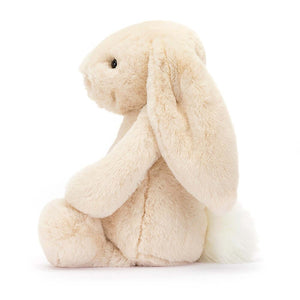 From the side the Jellycat Bashful Luxe Bunny Willow children's soft toy with its legs out in front and tail behind.