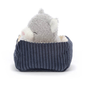 Side view of Jellycat Napping Nipper Cat. This image shows its cute and fluffy profile with a peaceful expression on its face, the kitten rests comfortably in a cosy cordy blue bed with beautiful buttercream lining.