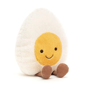 Jellycat boiled egg children’s soft toy that forms part of the amuseables range. The egg has a white body with yellow yolk face, a big smile and little brown corduroy legs. 