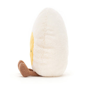 From the side the Jellycat amuseable Hard Boiled Egg children’s soft toy with his little brown legs sitting out in front. 