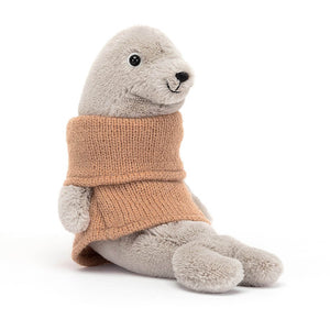 Jellycat Cozy Crew Seal children’s soft toy is covered head to toe is soft light brown fur and wears an apricot knitted jumper. 