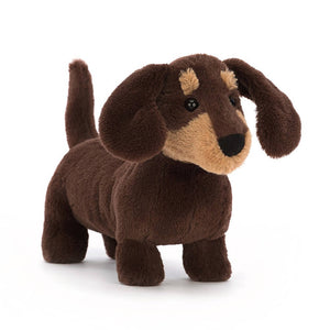 Jellycat Otto Sausage Dog children’s soft toy in small. He is covered in dark brown fur with caramel patches on his face. 