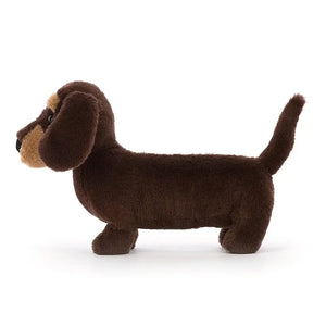 Jellycat Otto Sausage Dog in small size from the side. It is covered in dark brown fur and has tiny little legs. 