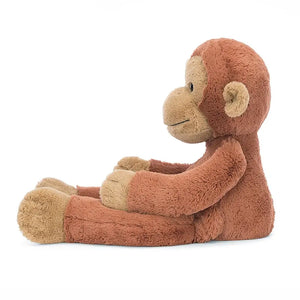 Jellycat orangutan from the side with his long, dangly arms and legs stretched out in front of him. 