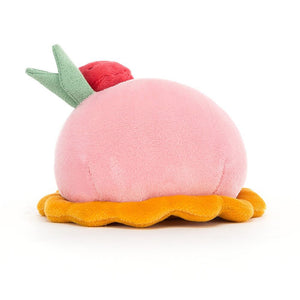 From behind the bright pink Jellycat Patisserie children’s soft toy. 