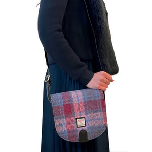 Lady wearing one of the Maccessori Harris Tweed Crossbody Bags over her shoulder. This one is in a pink and blue tartanlder. 