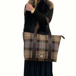 Lady holding a brown and blue tartan Maccessori Harris Tweed Tote Shopper from the handles. 