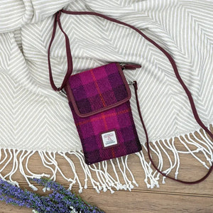 A pink and red tartan Harris Tweed crossbody shoulder bag from Maccessori sitting on top of a rug. 
