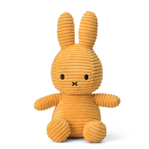 Sitting Miffy bunny rabbit children’s soft plush toy covered in yellow corduroy.